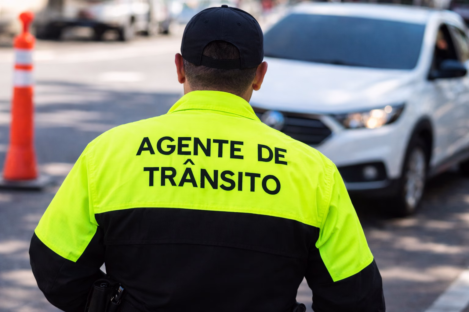 Agente de trânsito orientando veículos em via urbana com uniforme refletivo amarelo
